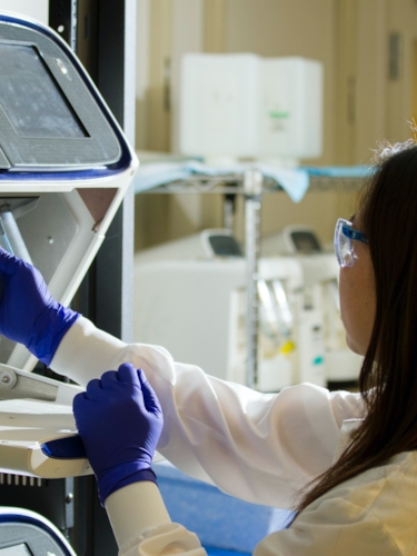 Ung kvinna arbetar med handskar i labbmiljö
