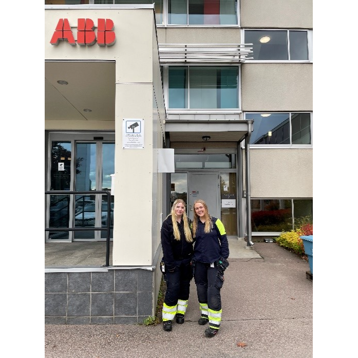 Två kvinnor står framför en byggnad där det står ABB på en pelare. Den ena kvinnan är handledare åt den andra genom Tekniksprånget. 