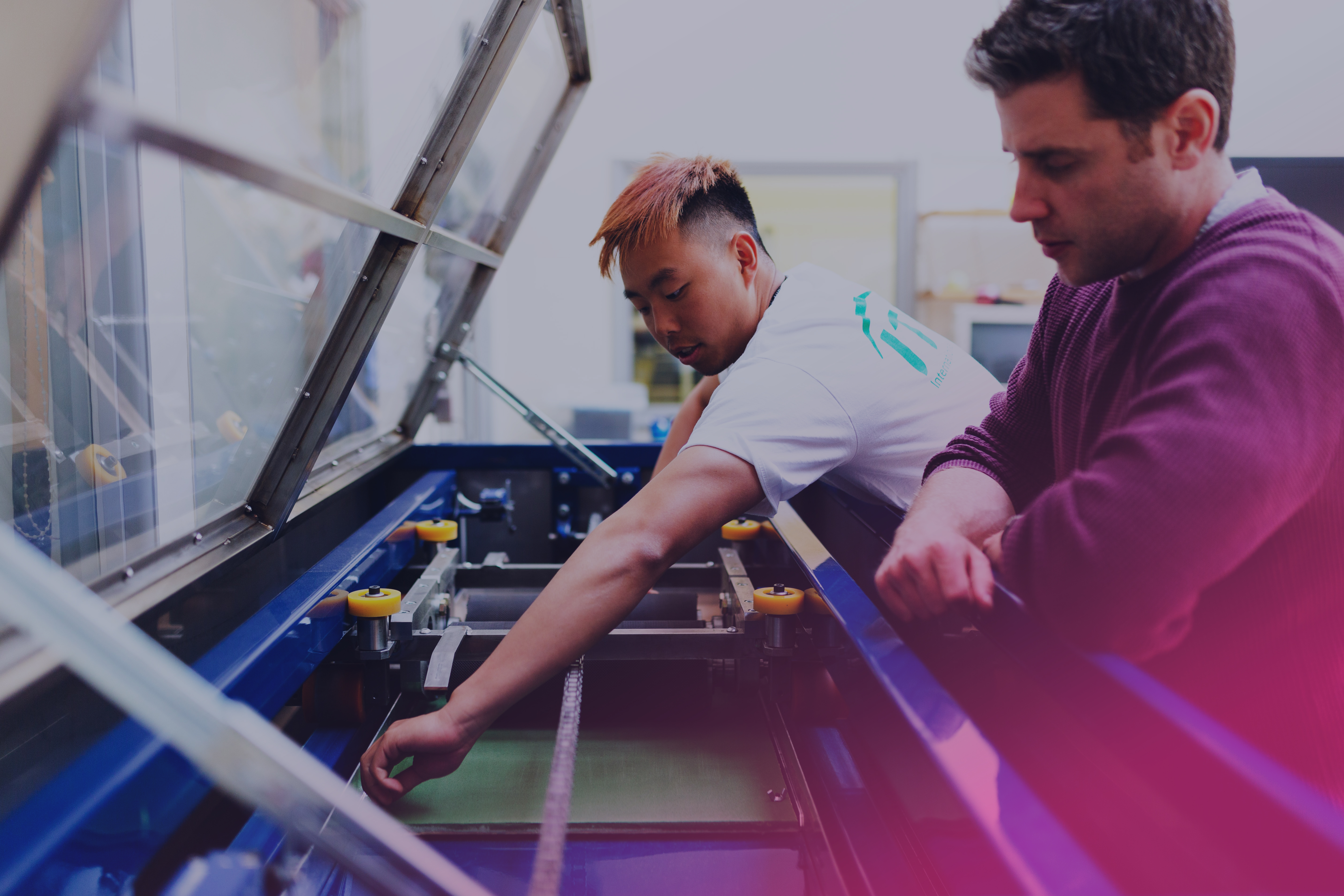 Två unga män arbetar vid en maskin.