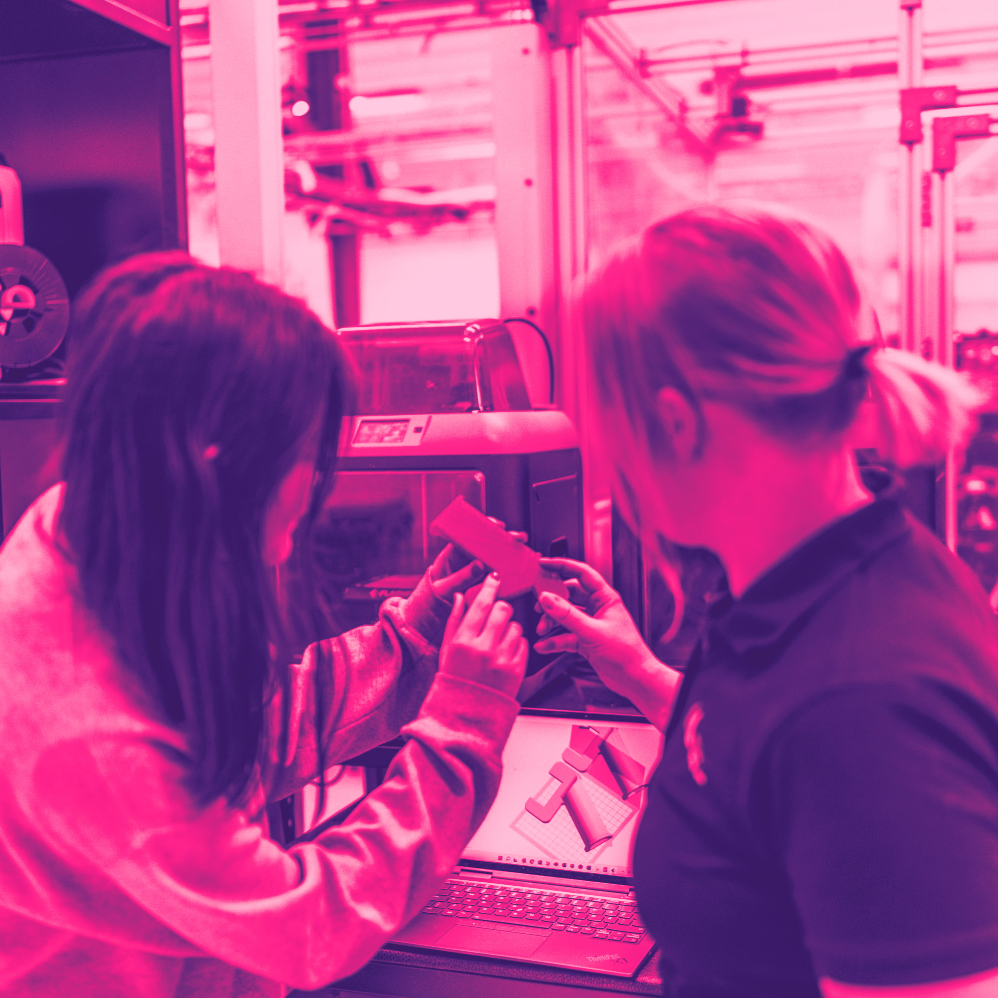 En ung kvinna får handledning av sin kvinnliga handledare vid en maskin med skärm. Med rosa filter