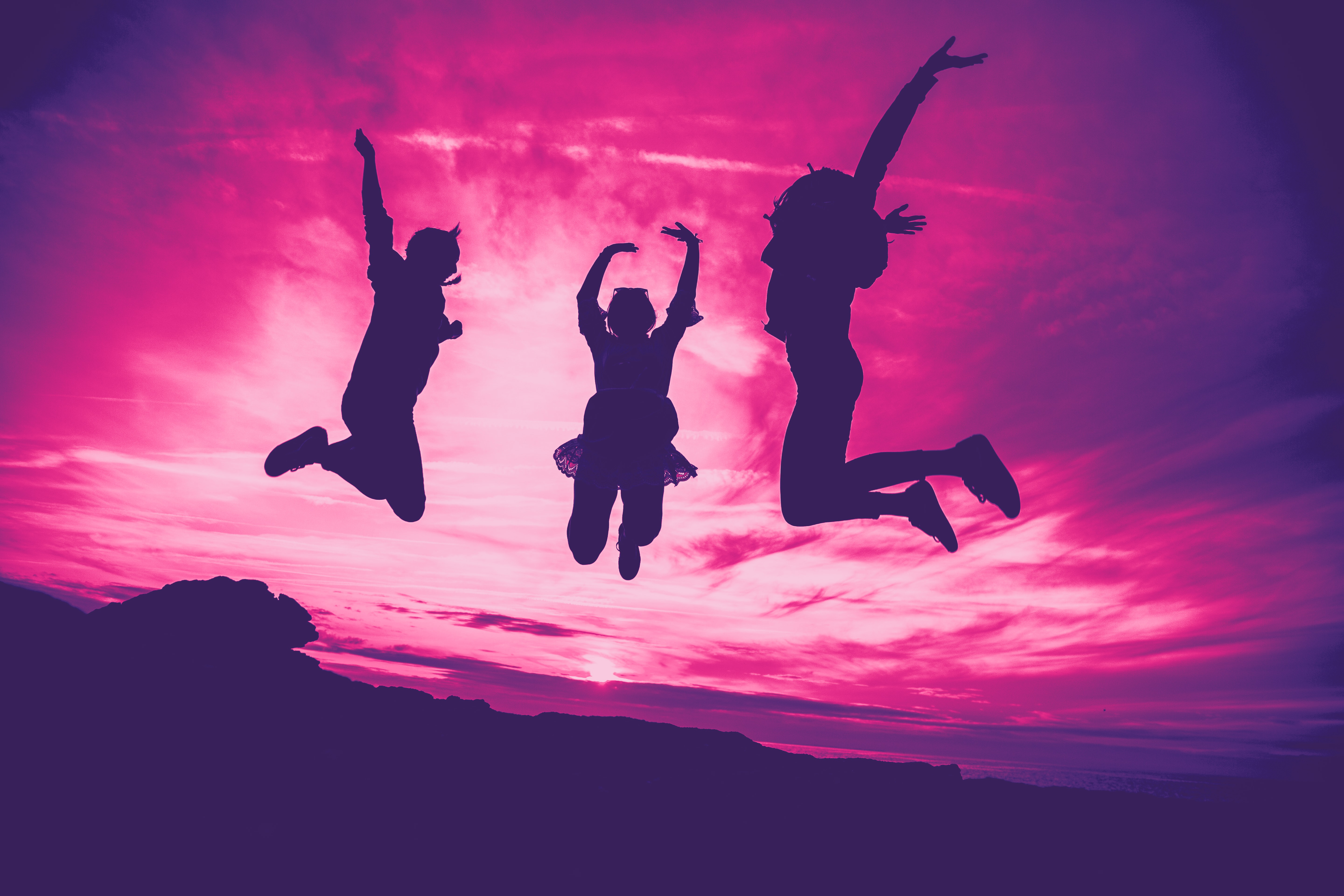 Bild på tre personer som hoppar med enbart siluetter synliga. Med rosa filter