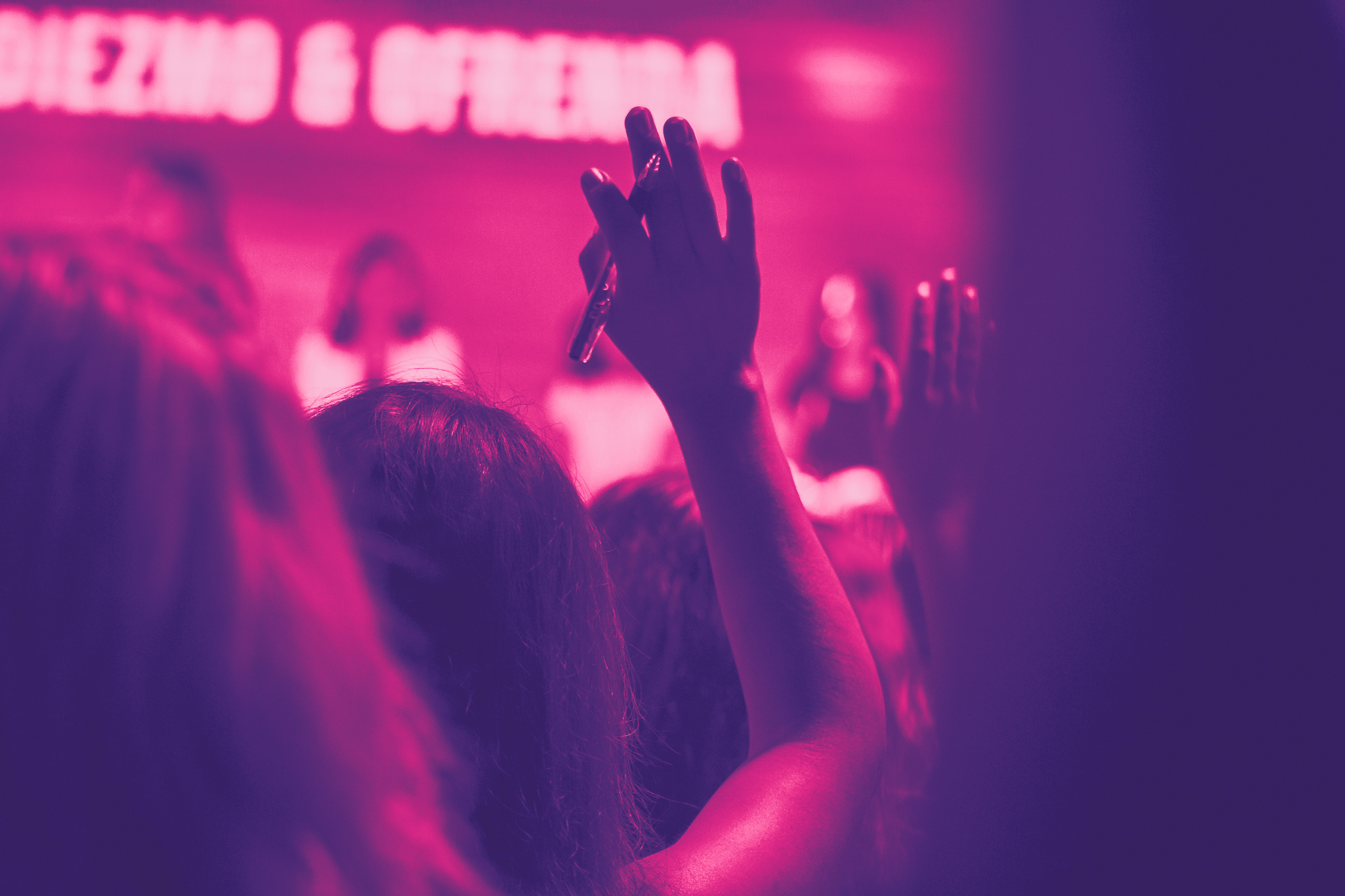 A person raises their hand at a seminar. With pink filter