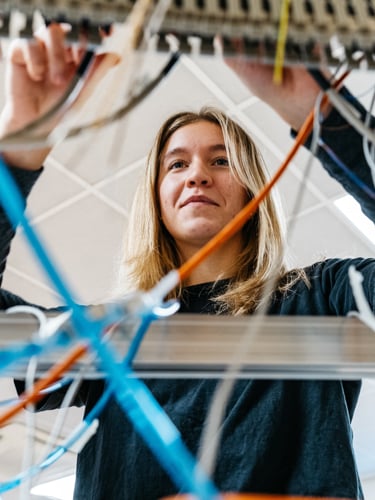 Young woman with long nails soldering together a circuit board.