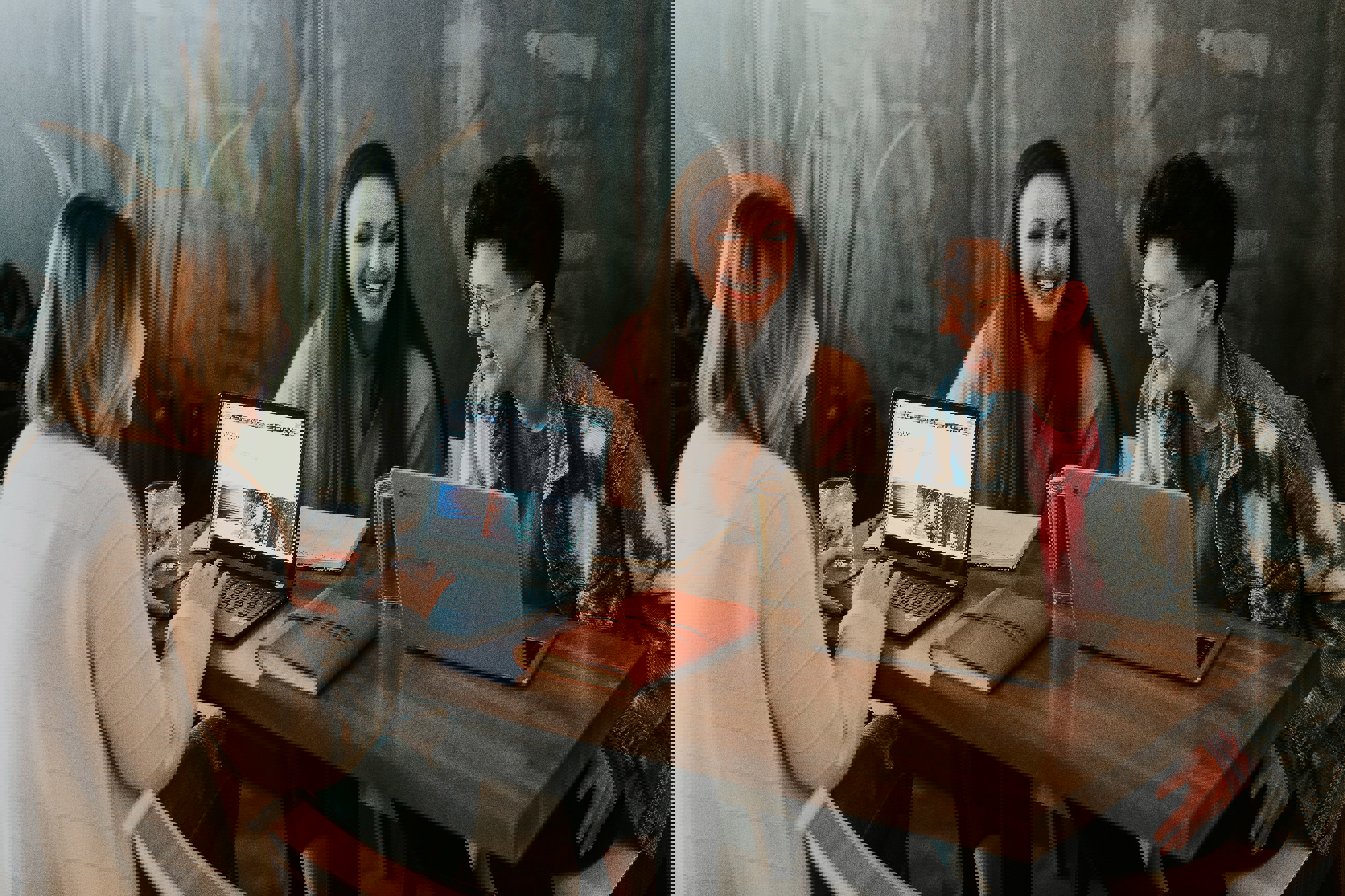 Three people laugh while working on their computers.