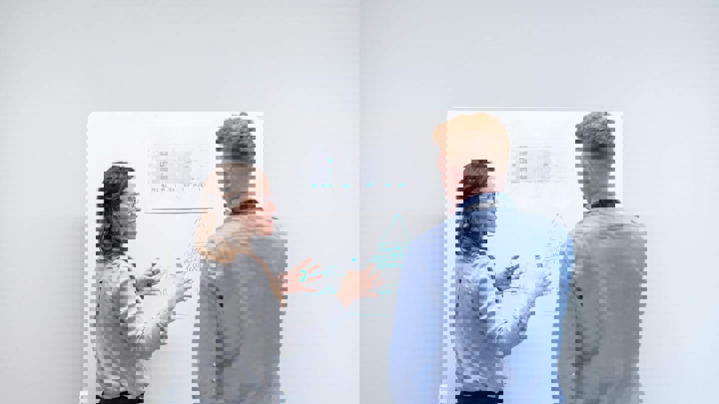 Ung kvinna presenterar på white board för sin handledare