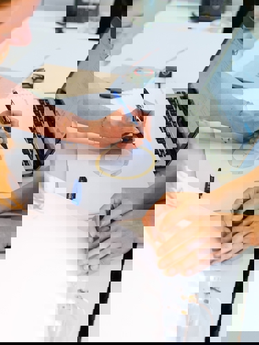 Three people working over a workbench, one of them appears to be painting on a drawing